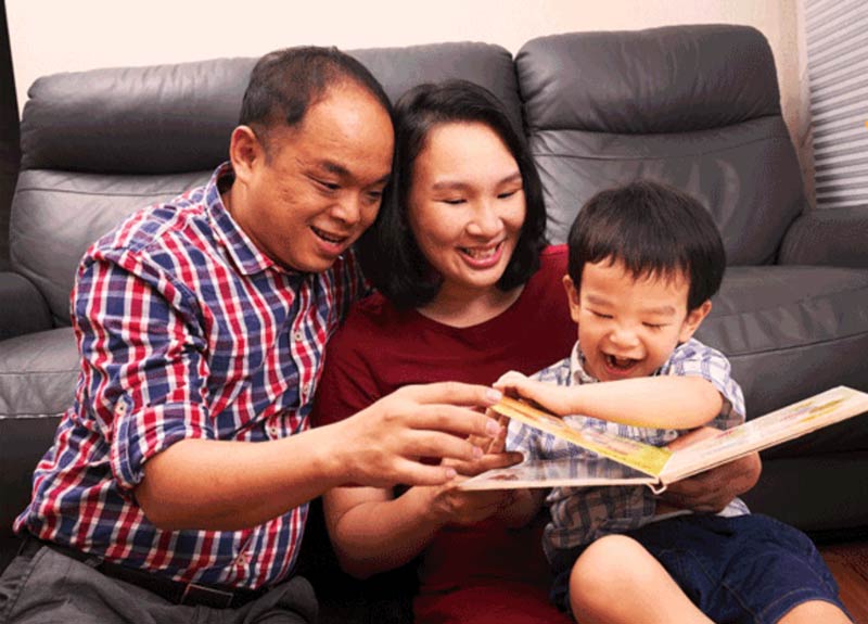 A chinese family with parent and child reading a book together